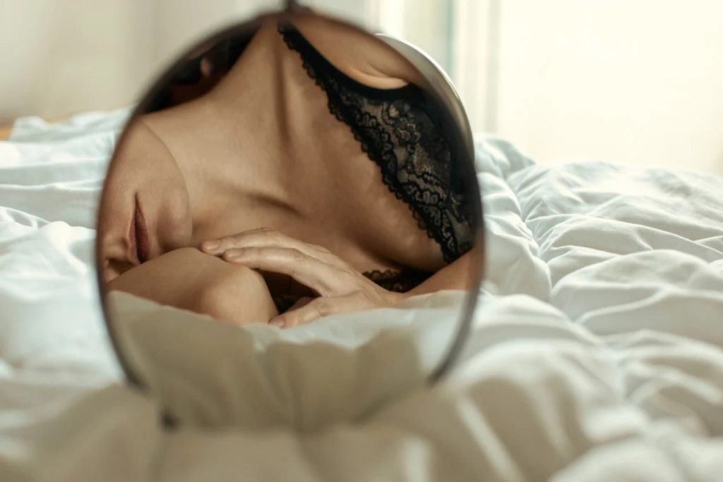 Woman in black sexy lingerie lying in front of the mirror-dress dark